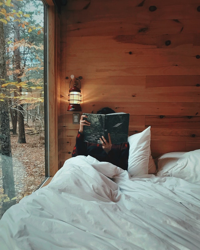  A book lover is reading a book in bed. he needs a book holder. 