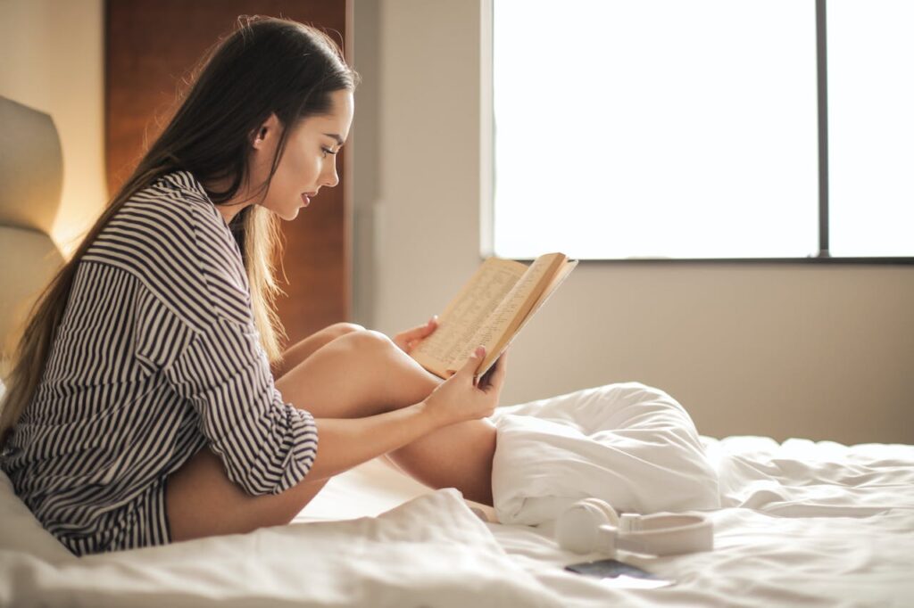 a girl is reading while sitting up in bed